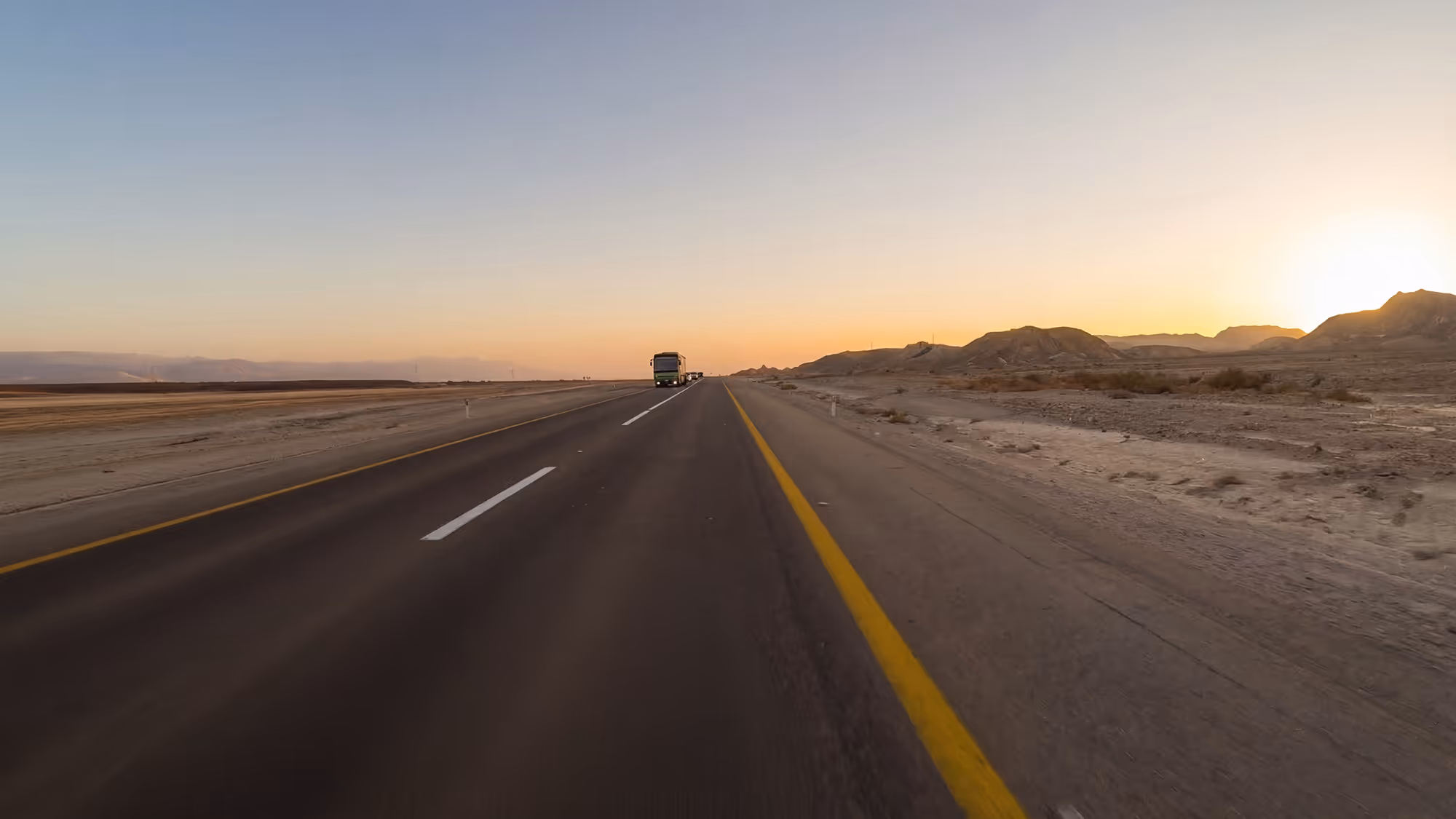 A long straight desert highway stretching toward the horizon at sunset, from the documentary series Highway 90