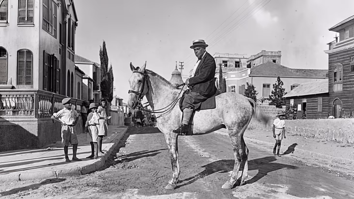 Historical black and white photograph of a man on horseback on a street in early 20th century Tel Aviv, from the documentary series Tel Aviv-Jaffa